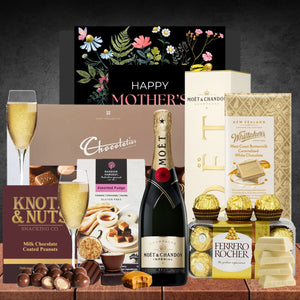 Gourmet gift basket with champagne, chocolates, and snacks on a wooden surface.