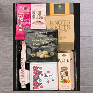 Gift box containing gourmet snacks and a "Happy Mother's Day" card. Items include marshmallows, truffle cheese bites, chocolates, and mixed nuts.