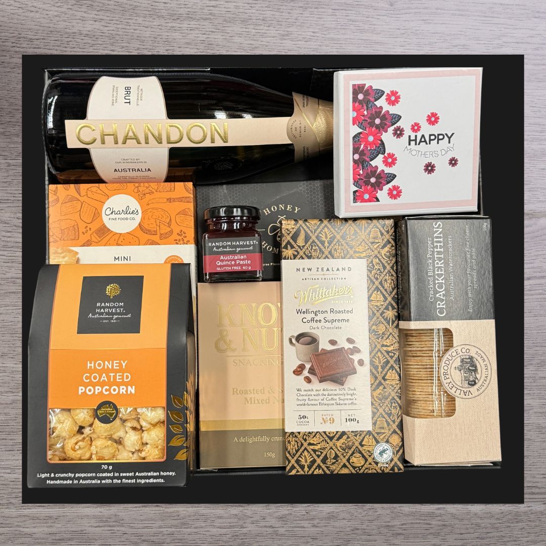 Gift box with a bottle of Chandon Brut, honey-coated popcorn, quince paste, mixed nuts, dark chocolate, crackers, and a floral "Happy Mother's Day" card.
