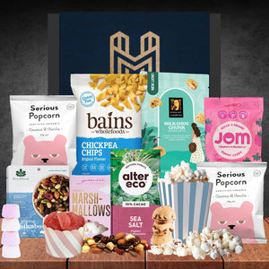 Assorted snack packages on a wooden surface with a dark background