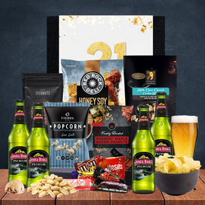 Gourmet gift set with beer, snacks, and a personalized card on a wooden surface.