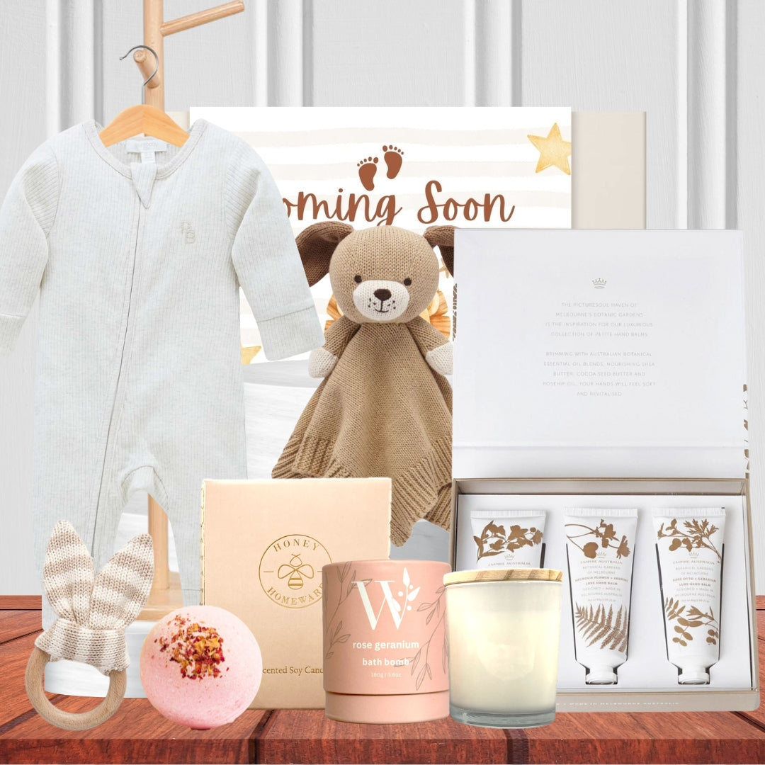 Collection of baby products including a teddy bear, baby onesie, and candles on a wooden surface.