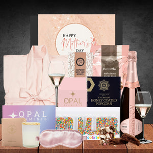 Mother's Day gift basket with wine, snacks, and a robe on a dark background