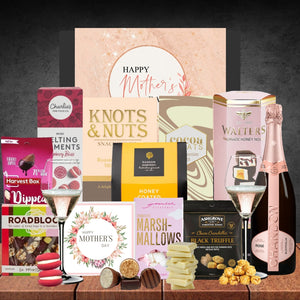 Assorted Mother's Day gift items including chocolate, flowers, and champagne on a wooden table.