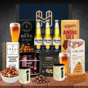 Assorted food and drink items including beer, nuts, and chocolate on a wooden surface.