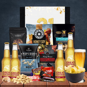 Gourmet gift basket with beer, snacks, and a 21st birthday card on a wooden surface.