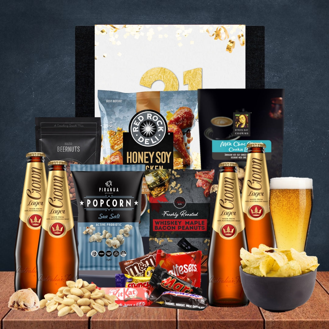 Gourmet gift basket with beer, snacks, and candies on a wooden surface.